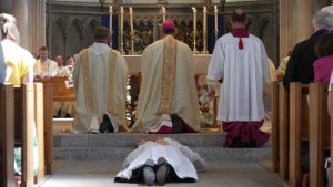 Deacon James lies prostrate on the floor while the bishop, priests, and parishioners recite the Litany of Saints